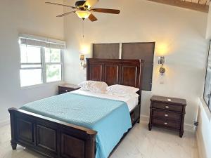 Oceanfront 3 bedrooms, 4beds, AC, WiFi, luxury villa في Woodlands: غرفة نوم بسرير ومروحة سقف