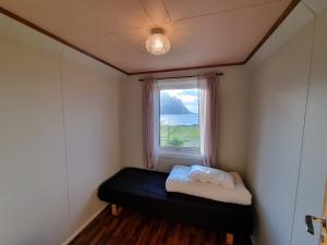 Habitación pequeña con ventana y cama negra. en Nappstraumen Seaview holiday home en Haug