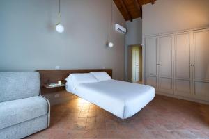 um quarto com uma cama branca e um sofá em Nèroli Bio Relais em Catânia