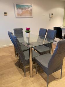 een glazen tafel met stoelen en een potplant erop bij Glenelg resort style beachside apartment in Glenelg