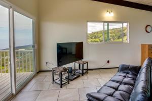 a living room with a couch and a tv at Captain Cook Bungalow with Panoramic Ocean Views! in Papa Bay Estates