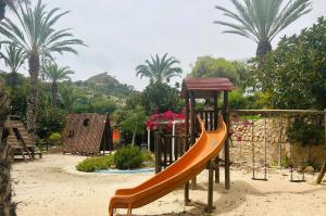 um parque infantil com um escorrega na areia com palmeiras em Sol Mediterráneo Palm Beach Two em Villajoyosa