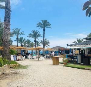 uma praia com palmeiras, mesas e guarda-sóis em Sol Mediterráneo Palm Beach Two em Villajoyosa