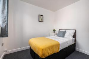 a bedroom with a bed with a yellow blanket on it at Hills Close in Mexborough