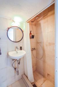uma casa de banho com um lavatório e um chuveiro com um espelho. em Mini Suite Roman Agora em Tessalônica