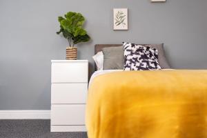 a bed with a yellow blanket next to a white dresser at Hills Close in Mexborough