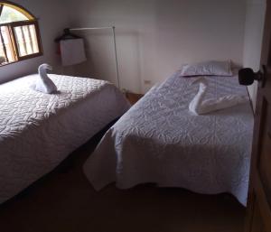 two swans sitting on a bed in a bedroom at MI CABAÑA DE DESCANSO in Cucaita +1 photo