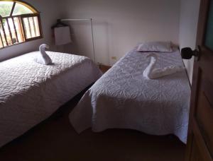 two swans sitting on a bed in a bedroom at MI CABAÑA DE DESCANSO in Cucaita