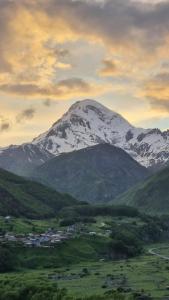 a snow capped mountain with a town in front of it at North Kazbegi in Stepantsminda