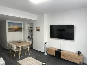 a living room with a table and a television on a wall at Appartement Justine in Blankenberge