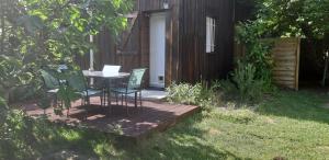 una mesa y sillas en una terraza de madera en un patio en La Grange - 5 couchages avec jardin et terrasse, en Le Tremblay-sur-Mauldre
