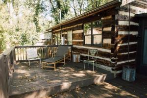 a porch of a log cabin with a bench and chairs at Downtown-Urban Cabin Unique Stay in Murfreesboro