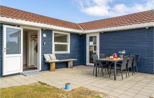 a blue house with a patio with a table and chairs at Kis in Fanø