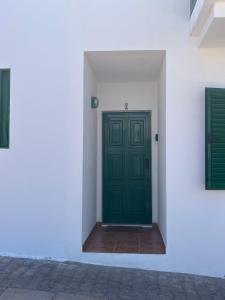 a green door on the side of a white building at Casa Noas in Playa Blanca
