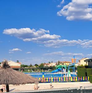 a swimming pool with a water park in the background at La Casa del Ciprés in Aldeamayor de San Martín