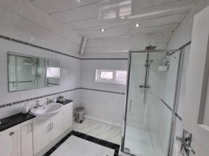 a white bathroom with a shower and a sink at Modern 3 bedroom house, 3 Bathroom, secure parking, Wi-Fi & Garden in Leeds