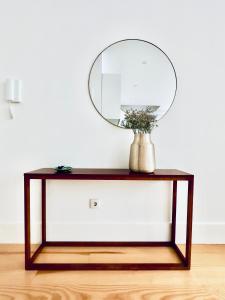 a table with a mirror and a vase with flowers at Vibrant Porto Apartments-Bonfim in Porto