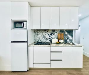 a white kitchen with white cabinets and a refrigerator at Vibrant Porto Apartments-Bonfim in Porto