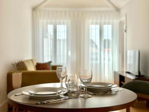einen Tisch mit Tellern und Weingläsern darauf in der Unterkunft Vibrant Porto Apartments-Bonfim in Porto