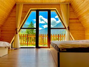 a bedroom with a large window in a wooden house at Villa Dardania in Peje
