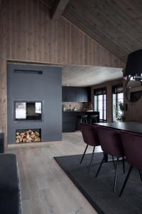 a living room with a fireplace and a table and chairs at Strandafjellet Panorama Lodge - Large Cabin with Majestic Mountain View in Stranda
