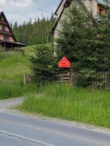 a red sign in the grass next to a house at Cyrwony Domek in Poronin