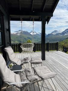斯特蘭達的住宿－Strandafjellet Panorama Lodge - Large Cabin with Majestic Mountain View，门廊配有椅子和秋千,享有山景。