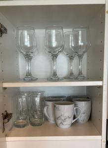 una fila di bicchieri da vino e tazze su uno scaffale di Glenelg resort style beachside apartment a Glenelg