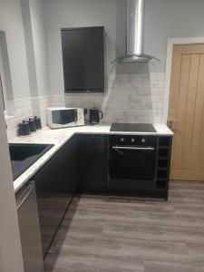 a kitchen with a black stove and a microwave at Beautiful MASONS HIDEAWAY studio apartment in Bridgend
