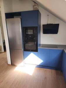 a kitchen with a refrigerator and a microwave at Blue Door Apartment Loft in Augustów