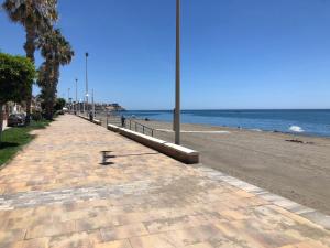 a sidewalk next to a beach with the ocean at Ático en la playa con terraza privada in Cala del Moral