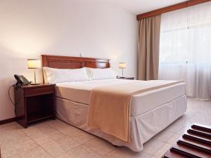 um quarto com uma cama grande e um telefone em Hotel Central Santa Maria em Santa Maria