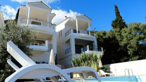 a white building with a swimming pool and a white chair at Villa Maria PF in Nydri