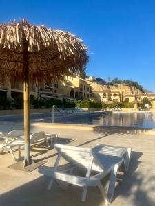 duas cadeiras e um guarda-sol junto a uma piscina em Brisa Marina, Altea em Alicante