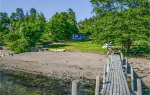 eine Holzbrücke über einen Strand mit einem Haus im Hintergrund in der Unterkunft Amazing Home In Drbak With Kitchen in Drøbak