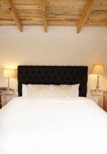 1 dormitorio con cama blanca y cabecero negro en Cabaña El Encino III en Real del Monte, en Mineral del Monte