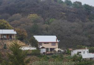 una casa en una colina frente a una montaña en Cabaña El Encino III en Real del Monte, en Mineral del Monte