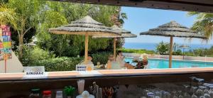 un bar avec deux parasols et une piscine dans l'établissement Almar Hotel Apartamento, à Albufeira