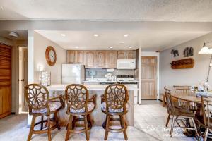 a kitchen with wooden cabinets and a table and chairs at RECENTLY UPDATED Ski In & Out Condo with Heated Garage Parking and VIEWS! TE303 in Breckenridge