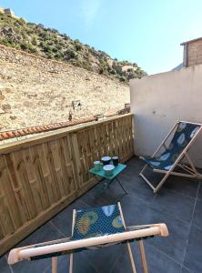 une terrasse avec 2 chaises, une table et une clôture dans l'établissement Appartement Le Fort Vue montagne, à Villefranche-de-Conflent