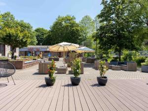 a patio with three potted plants and umbrellas at Bungalow in Waxweiler in the Southern Eifel in Waxweiler