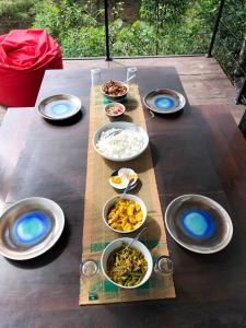 una mesa con tazones y platos de comida. en Dumbara Breeze, en Hunnasgiriya