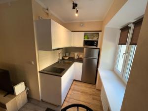 a small kitchen with white cabinets and a stainless steel refrigerator at Lovely and cozy apartment in central Tartu in Tartu