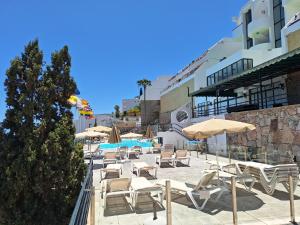 a patio with tables and chairs and umbrellas at Horizon Views - Excellent location with ocean view in Puerto Rico de Gran Canaria