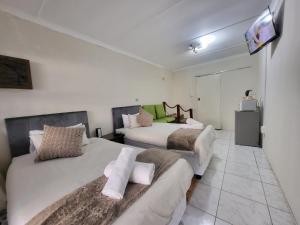 a bedroom with two beds and a tv on the wall at Generosa of the North in Durban