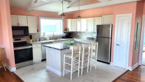 a kitchen with an island with bar stools at 8018 Beach Rd, Semi-Oceanfront, Pool/Hot Tub in Nags Head