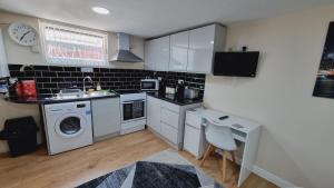 a kitchen with a sink and a washing machine at Lovely studio-flat with free parking, free WiFi. in Leeds