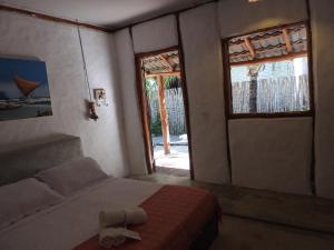 1 dormitorio con cama, ventana y puerta en Pousada Santa Aldeia en Barra Grande