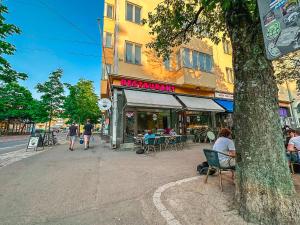 uma rua com pessoas sentadas em cadeiras fora de um restaurante em Residential Hotels Helsinki Penthouse em Helsínquia