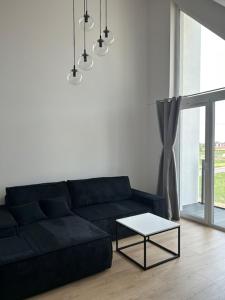 a living room with a black couch and a table at Apartament w Ustroniu Morskim Słoneczne Apartamenty in Ustronie Morskie